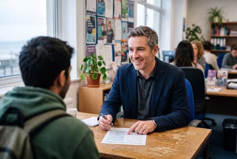 Careers adviser talking a student through options at his desk — Person `main_image`, staff/support.